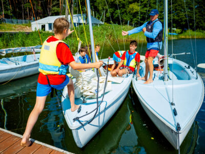 Dzieci uczą się żeglarstwa na jeziorze. Szkolenie żeglarskie dla młodzieży.