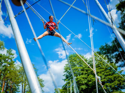 Dziewczyna skacze na trampolinie bungee na tle błękitnego nieba.