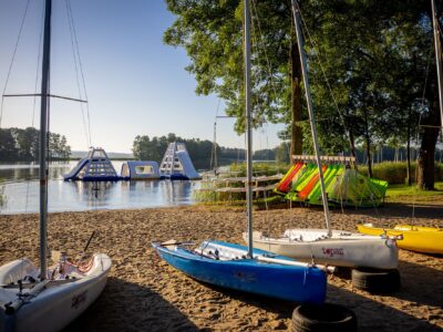 Łódki żaglowe na plaży, wodny plac zabaw i jezioro. Idealne miejsce na letni wypoczynek.