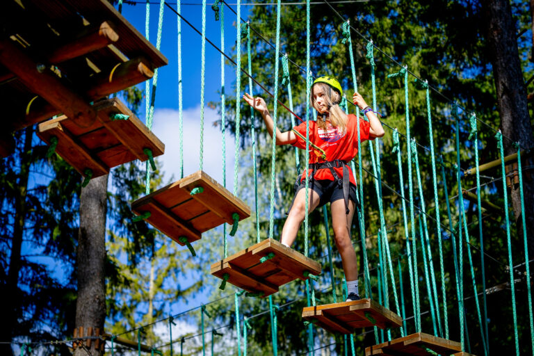 Dziewczynka na parku linowym. Zabawa na wysokości, aktywny wypoczynek.