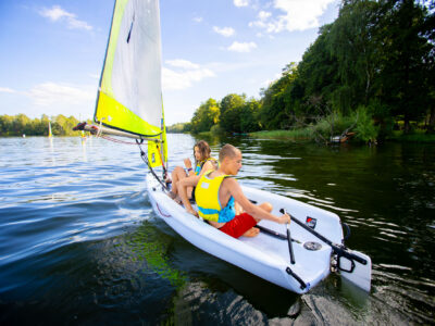 Dzieci żeglują na jeziorze w słoneczny dzień.