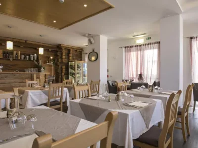 Przytulna restauracja z drewnianymi elementami, stoły nakryte do posiłku. Idealne miejsce na relaks.