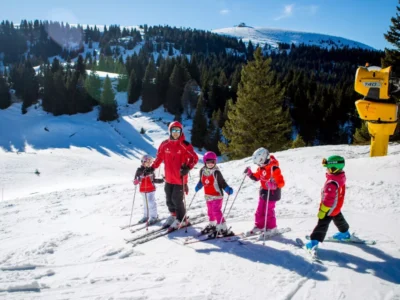 Rodzina na nartach w górach. Instruktor i dzieci na stoku. Zimowy sport i aktywność.