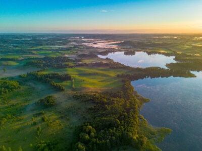 Widok z lotu ptaka na jezioro i pola o wschodzie słońca. Malowniczy krajobraz.
