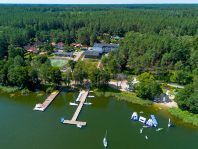 Malownicze jezioro z pomostem, żaglówkami i atrakcjami wodnymi. Idealne miejsce na wypoczynek.