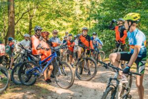 Grupa dzieci w kaskach na rowerach górskich w lesie. Przygoda i sport na świeżym powietrzu.