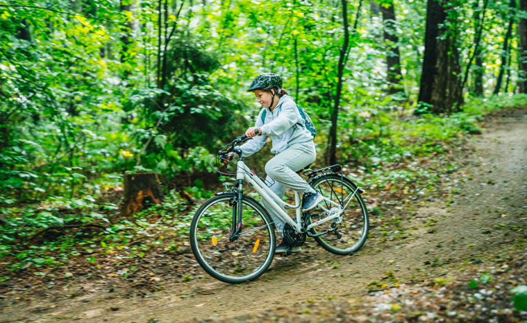Dziewczynka na rowerze w lesie. Jazda na rowerze, aktywny wypoczynek, natura.