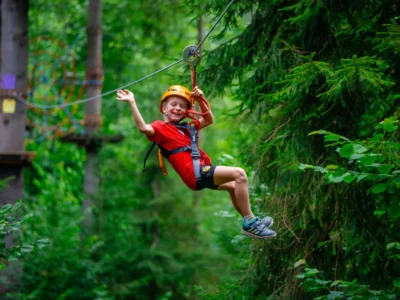 Chłopiec zjeżdża na tyrolce w parku linowym.