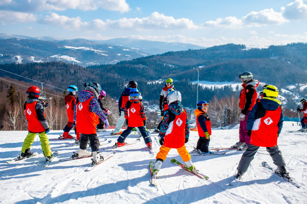 Dzieci na nartach uczą się jeździć na stoku górskim.