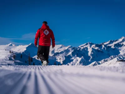 Narciarz w czerwonej kurtce na tle ośnieżonych gór.