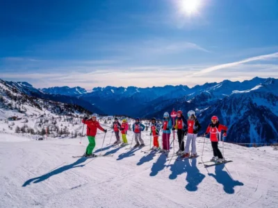 Grupa narciarzy na stoku, słoneczny dzień, piękne góry. Nauka jazdy na nartach dla dzieci.