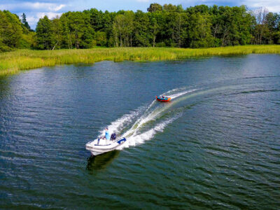 Łódź motorowa ciągnie dmuchaną zabawkę po jeziorze. Wodne szaleństwo na Mazurach.
