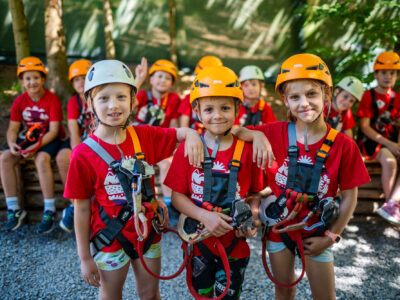 Dzieci w kaskach i sprzęcie wspinaczkowym gotowe na przygodę. Bezpieczeństwo i zabawa!