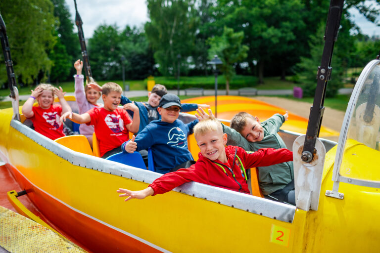 Radosne dzieci na żółtej kolejce górskiej w parku rozrywki. Zabawa i uśmiechy!