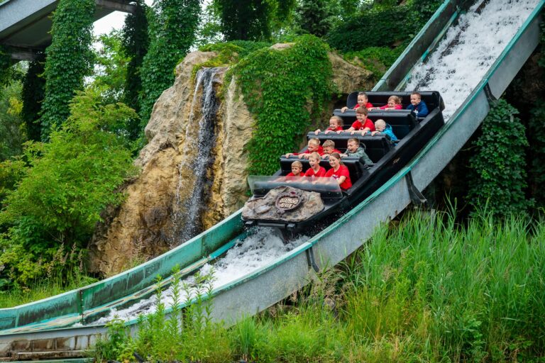 Dzieci z radością zjeżdżają łódką po wodnej zjeżdżalni. Park rozrywki, atrakcje wodne.