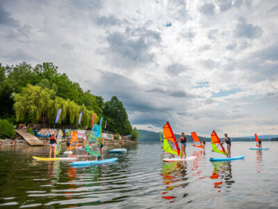 Zajęcia z windsurfingu na jeziorze. Ludzie uczą się pływać na deskach z żaglami.