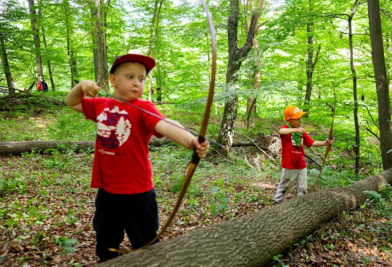 Dzieci ćwiczą łucznictwo w lesie.