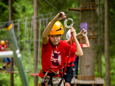Chłopiec w kasku na parku linowym, pokonuje trasę zjazdową.