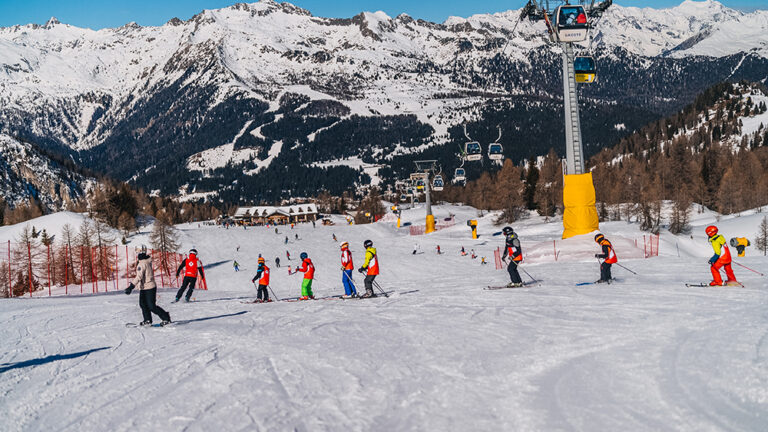 Narciarze na stoku z wyciągiem krzesełkowym i ośnieżonymi górami. Idealne warunki do jazdy na nartach!