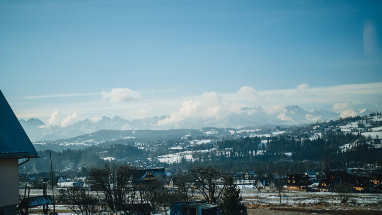 Zimowy krajobraz z ośnieżonymi górami i domkami.