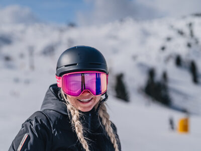 Kobieta w goglach narciarskich i kasku na stoku. Narty, snowboard, zimowy sport.