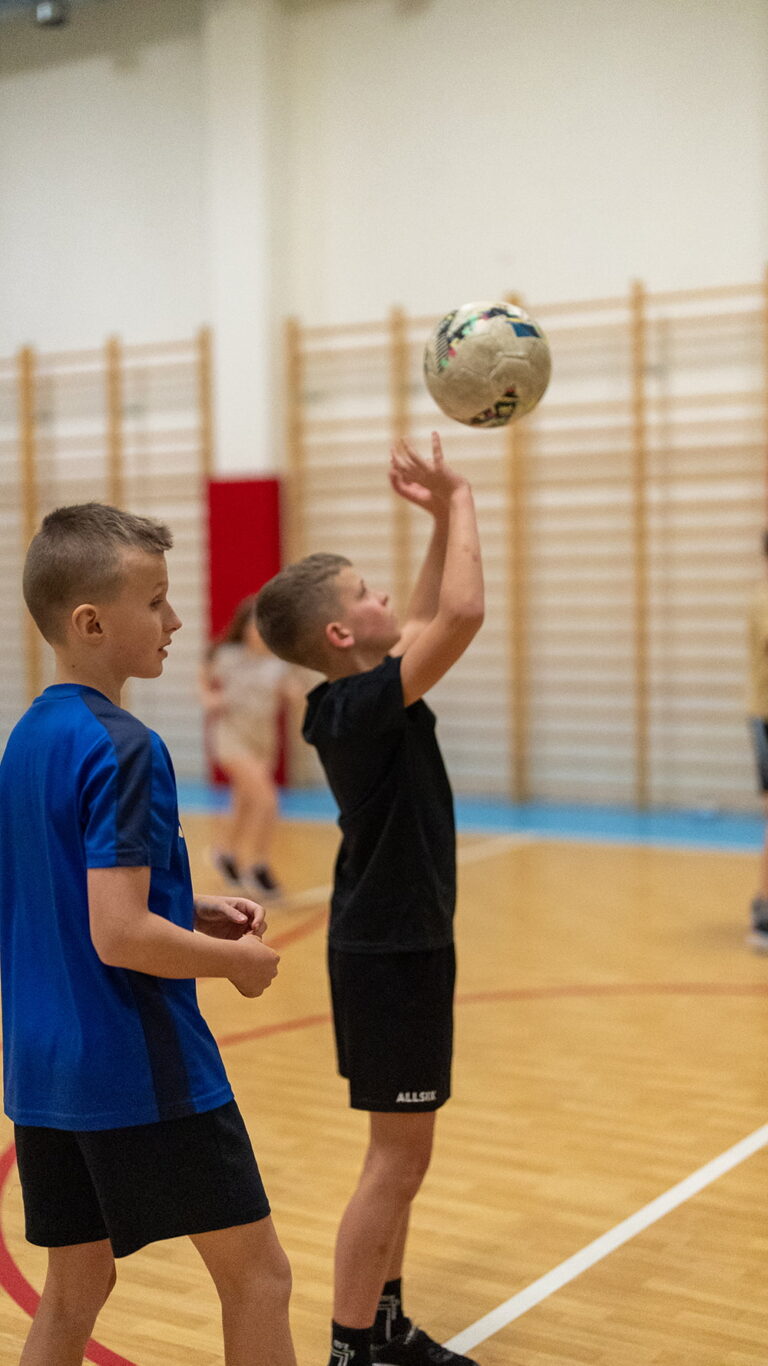 Chłopiec rzuca piłką do koszykówki na sali gimnastycznej.