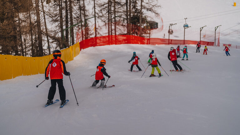 Dzieci na nartach na stoku. Nauka jazdy na nartach dla najmłodszych.