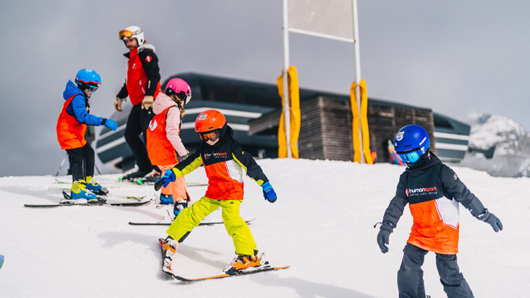Dzieci uczące się jeździć na nartach z instruktorem. Narciarstwo dla dzieci, sporty zimowe, nauka jazdy na nartach.