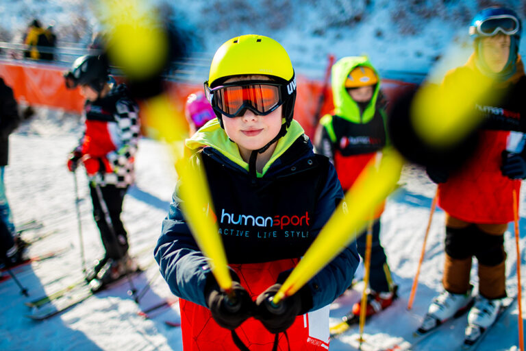 Chłopiec w żółtym kasku i goglach narciarskich, gotowy do jazdy na nartach.