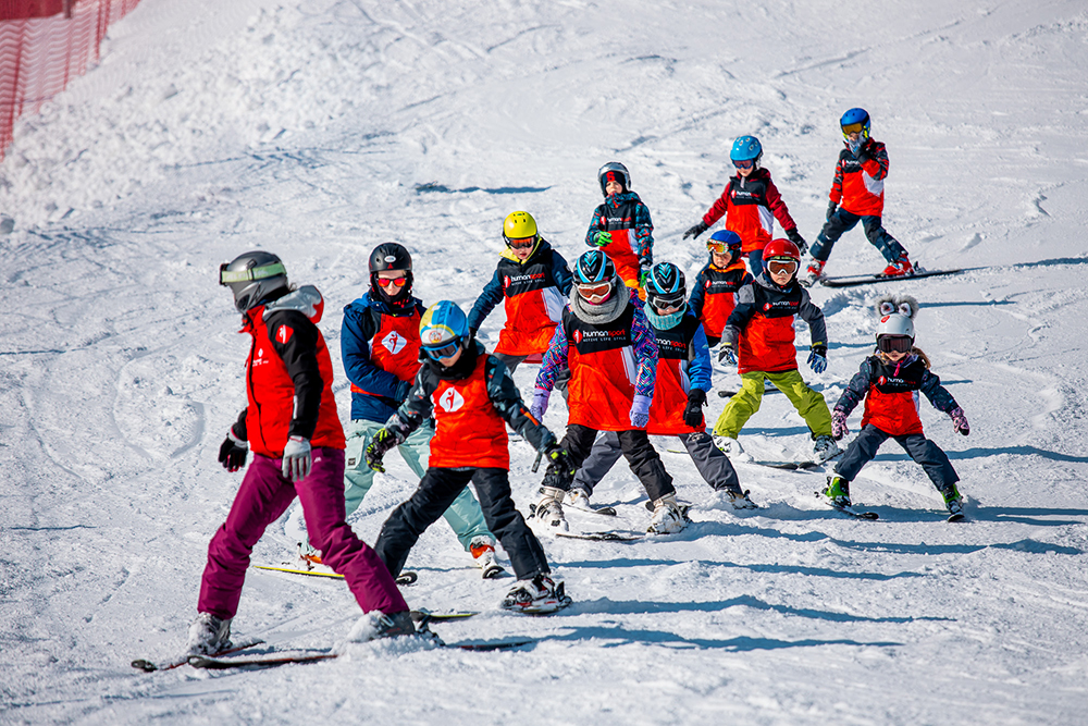 Dzieci na nartach w słoneczny dzień. Nauka jazdy na nartach dla najmłodszych.