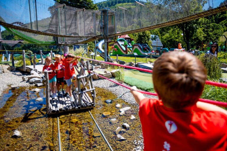Dzieci na drewnianym moście w parku linowym. Zabawa na świeżym powietrzu.
