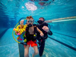 Podwodna przygoda: chłopiec i instruktor nurkowania w basenie. Nauka nurkowania dla dzieci.