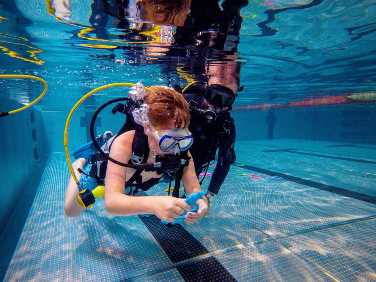 Podwodna nauka nurkowania: dziecko z instruktorem w basenie.