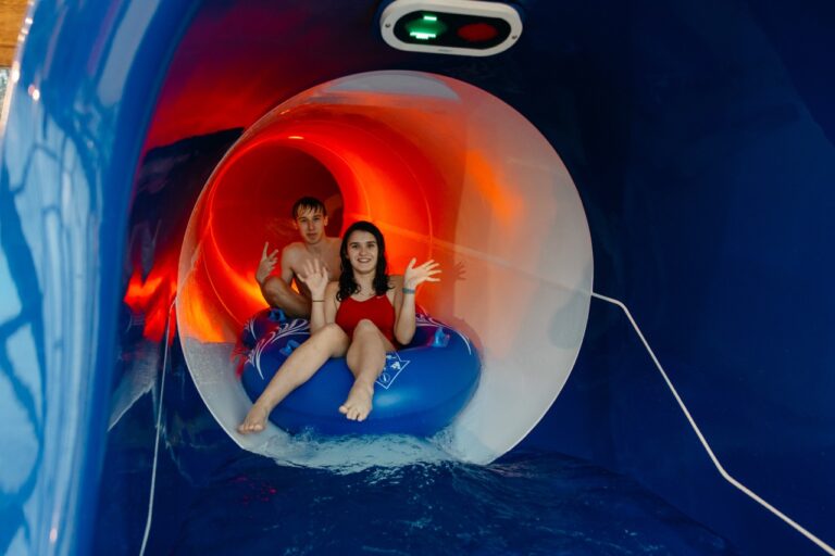 Dwoje nastolatków na pontonie w podświetlonym tunelu zjeżdżalni