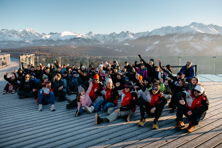 Grupa uczestników obozu narciarskiego na tarasie widokowym, w tle Tatry